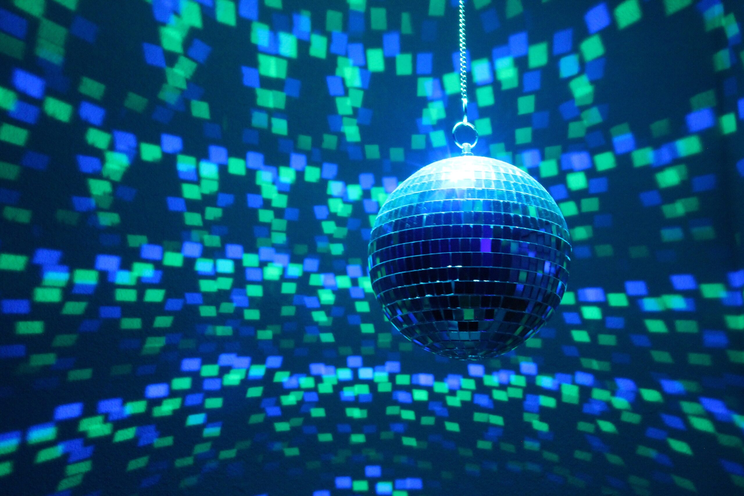 Hangende discobal die blauwe en groene lichtvlakjes over de muren en het plafond werpt in een donkere zaal