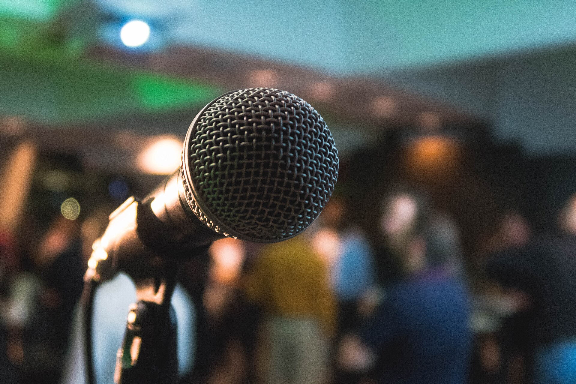 Microfoon op een standaard met wazige lichtjes van een karaokeavond op de achtergrond