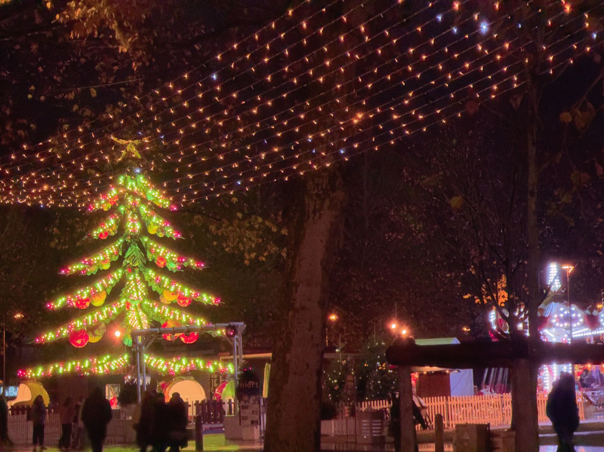 Verlichte kerstboom en lichtsnoeren op een plein in de avond