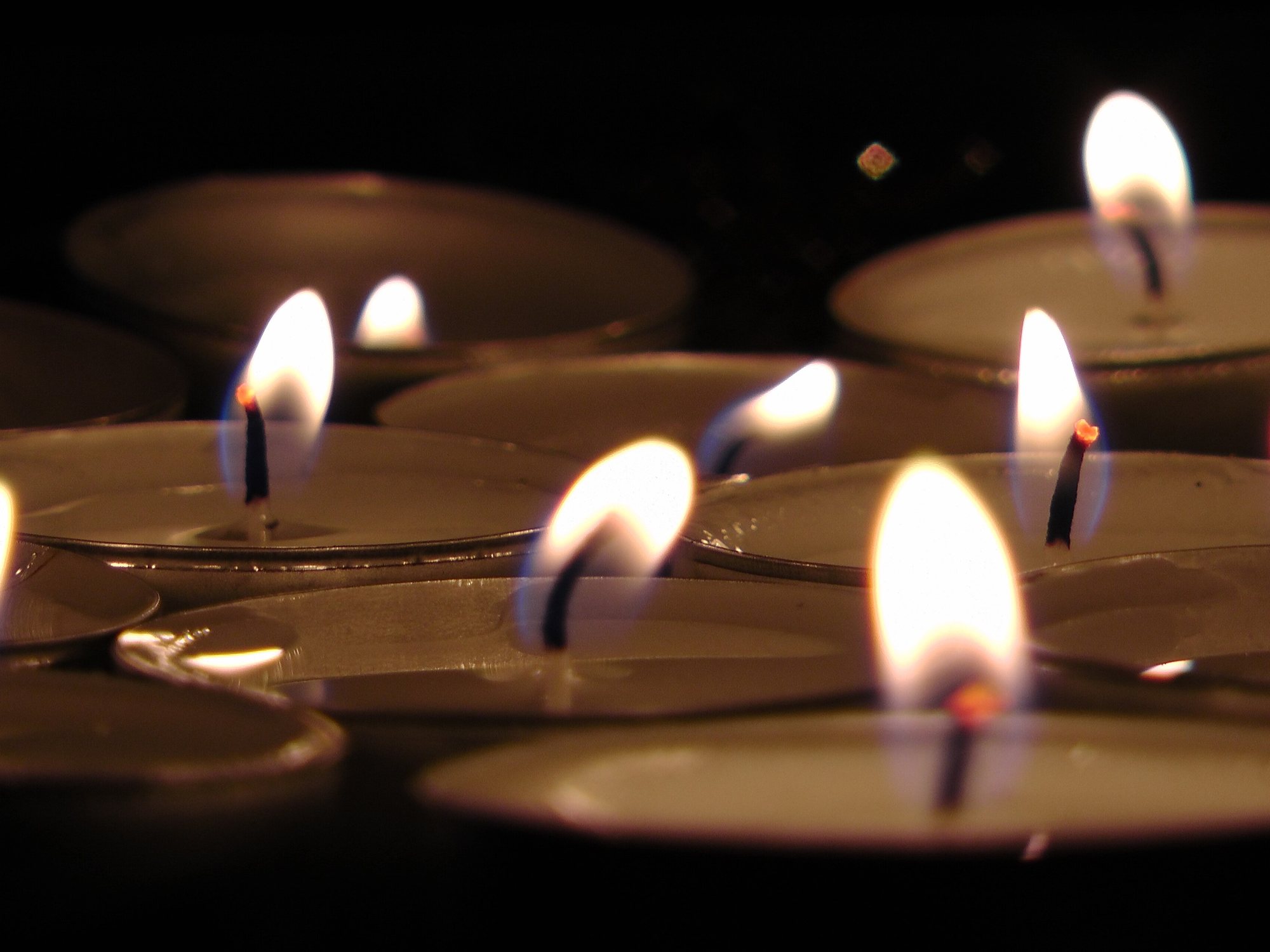 Een groep brandende waxinelichtjes in het donker, ter illustratie bij de Lichtjesavond Lansingerland