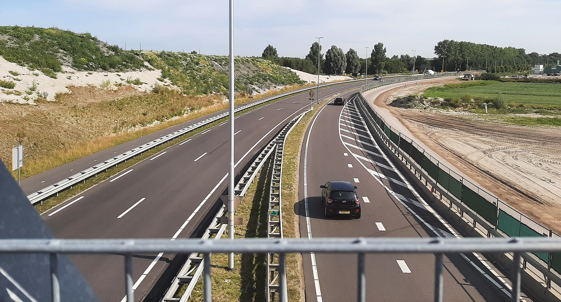 De N209 bij Bergschenhoek gezien vanaf een viaduct, met een auto op de rijbaan en vangrails langs de weg