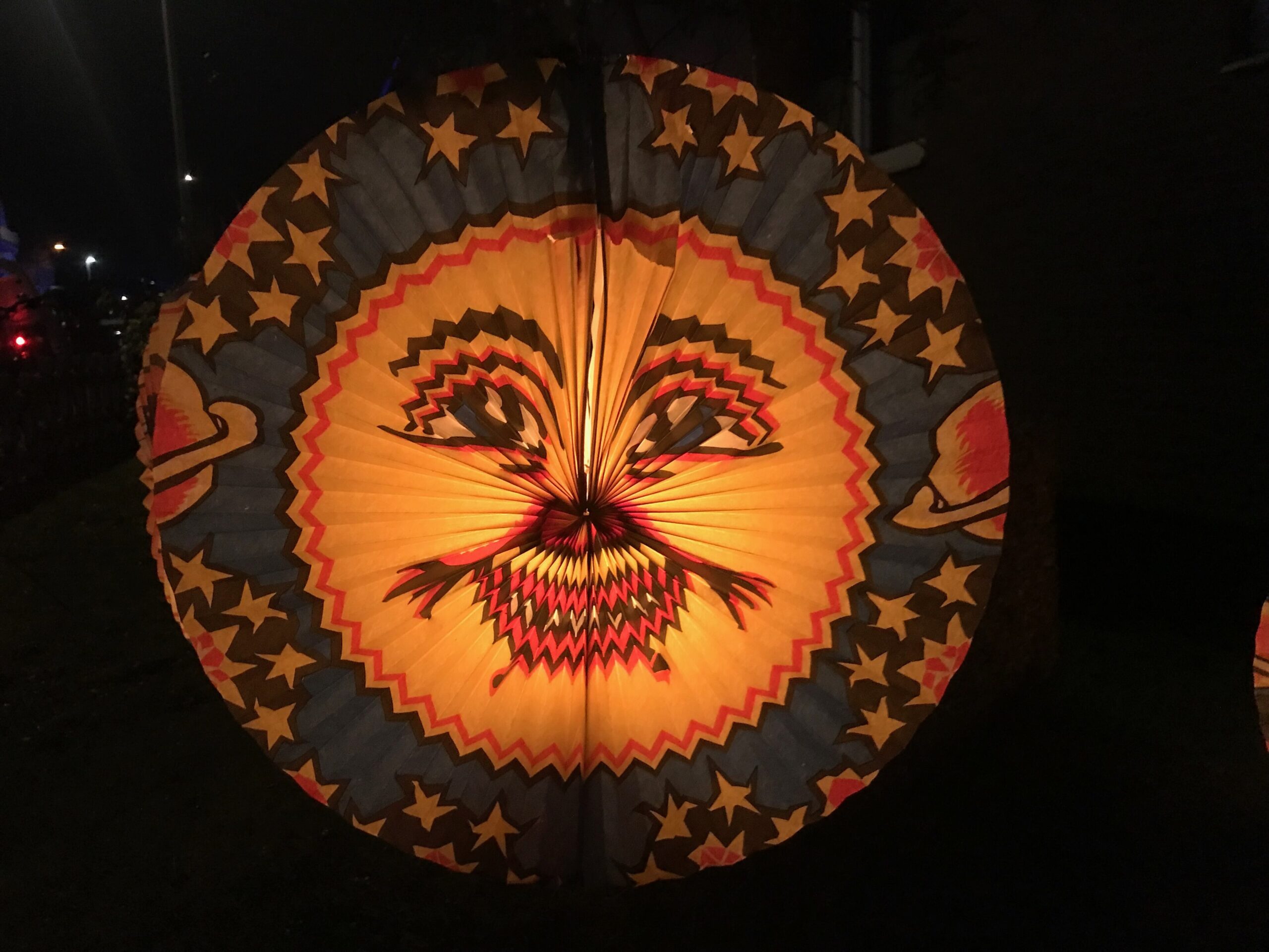 Verlichte papieren lampion met sterren en een gezicht in het donker, zoals kinderen die dragen met Sint Maarten
