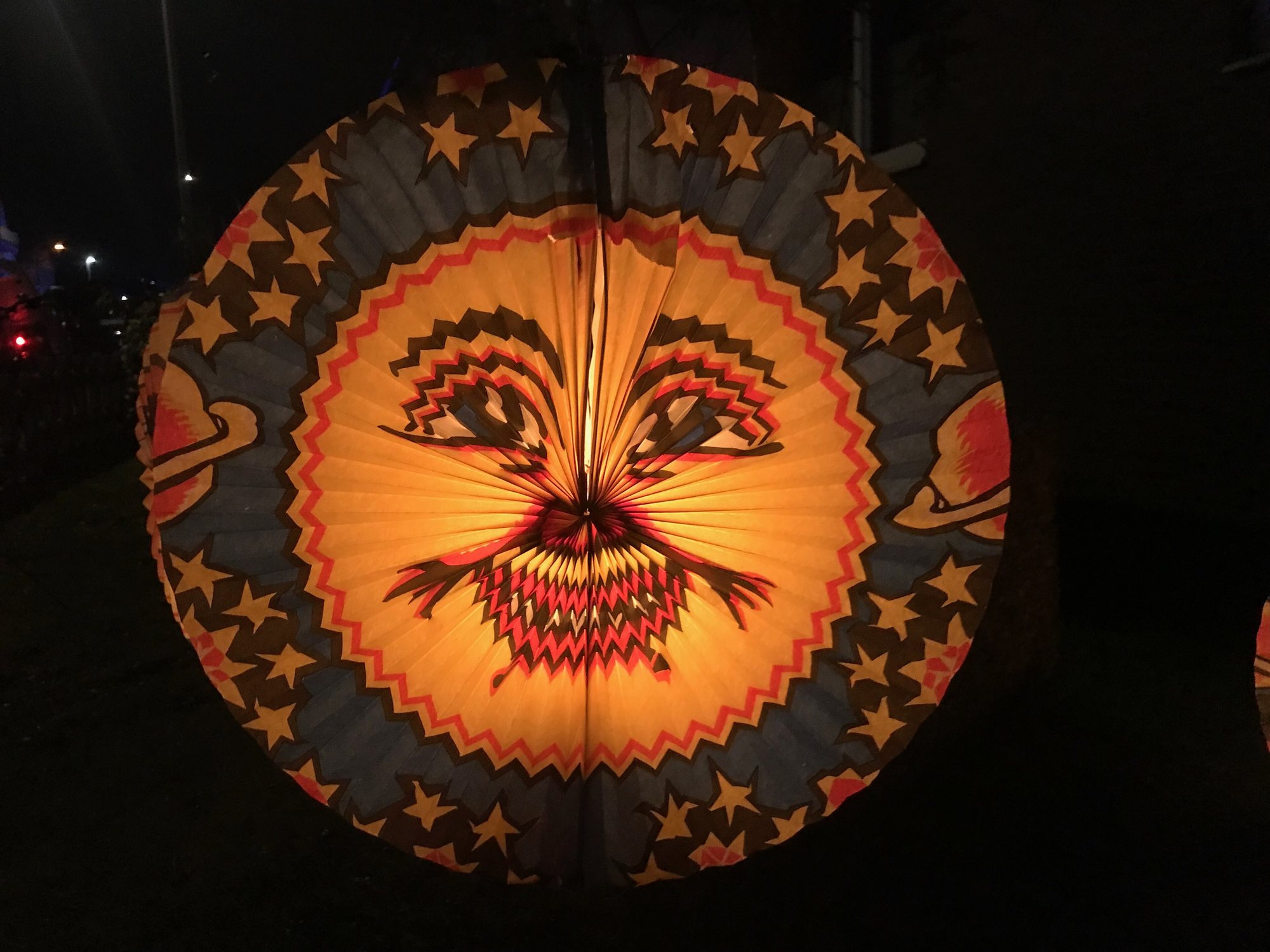 Brandende papieren lampion met een gezicht en sterren in het donker