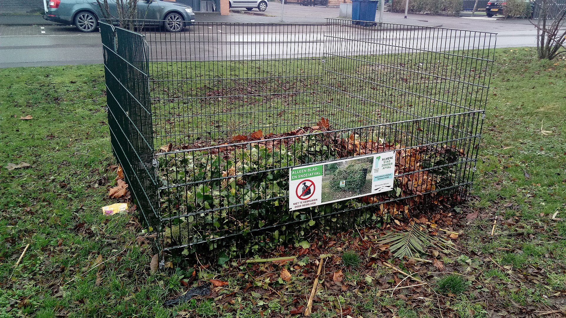 Container met blad en snoeiafval op een grasveld