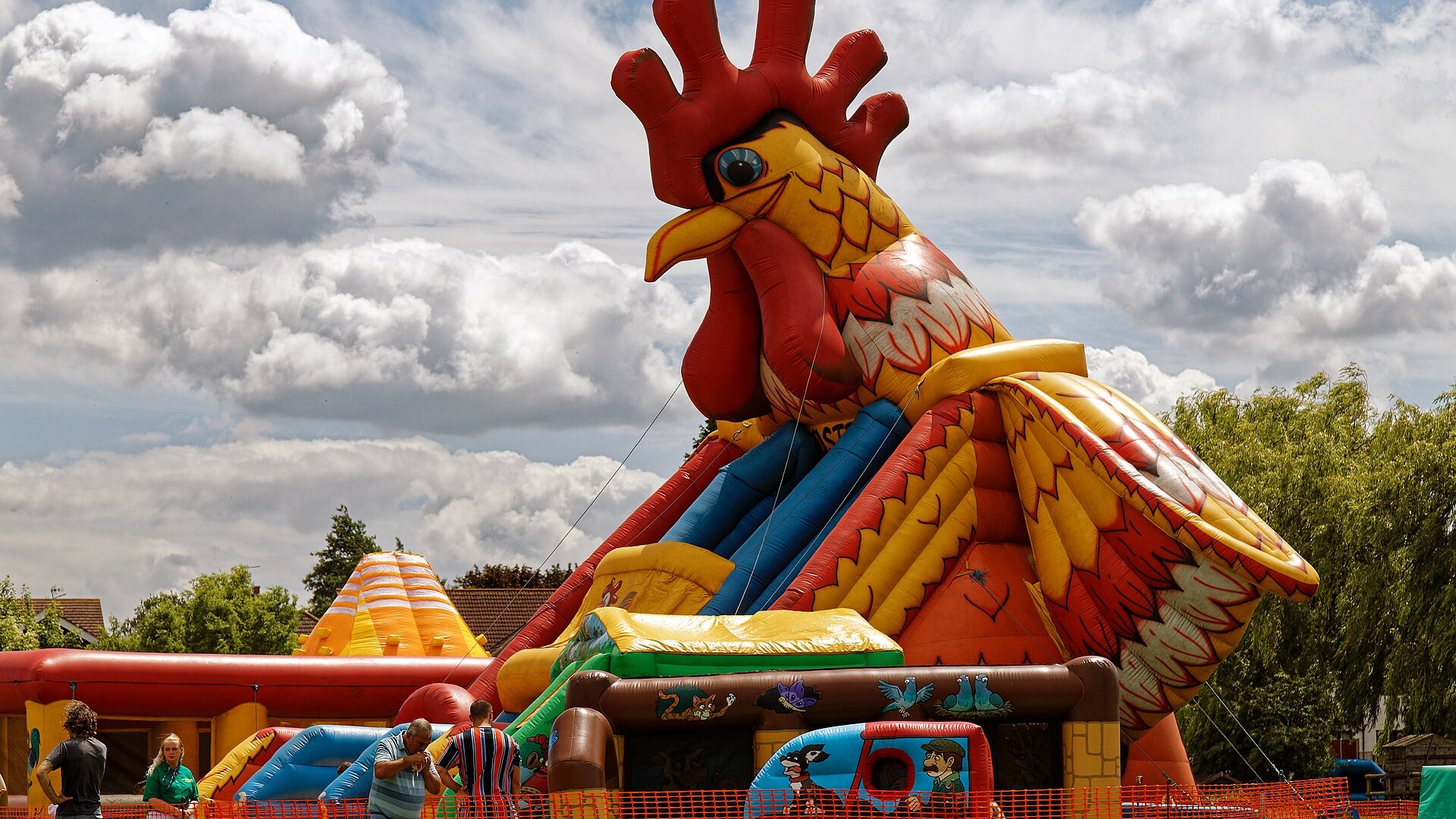 Kleurrijk springkussen met glijbaan en een grote haan